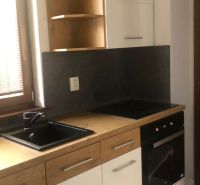 Küchenzeile in einer 2-Zimmer-Wohnung mit schwarzem Spülbecken und weißen Schränken.