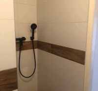 Duschkabine mit Keramikfliesen und Duschkopf in einer 2-Zimmer-Wohnung.