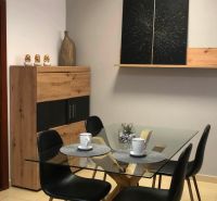 Glastisch mit vier Stühlen, Dekorationen und Regal in einer 2-Zimmer-Wohnung.
