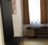 Flur in einer 2-Zimmer-Wohnung mit Bänken und Garderobe, helle Vorhänge, beiger Boden.
