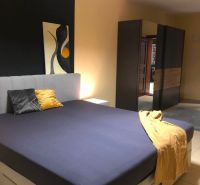 Schlafzimmer mit Doppelbett, Kleiderschrank und abstrakter Kunst in einer 2-Zimmer-Wohnung.
