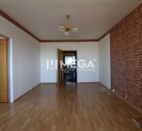 Ein Zimmer in einer 3-Zimmer-Wohnung mit einem Holzboden und einer Wand im Ziegelmuster.