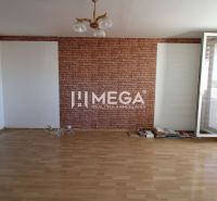 Ein Zimmer mit Ziegelverkleidung, einem Holzboden und einem großen Fenster in einer 3-Zimmer-Wohnung.