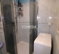 Badezimmer in einer 3-Zimmer-Wohnung mit Fliesen, Duschkabine und Waschmaschine.