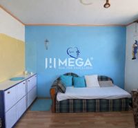 Ein Zimmer mit blauer Wand, Sofa und Schrank in einer 3-Zimmer-Wohnung mit Holzboden.