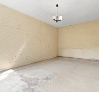 Leerer Raum mit Tapeten, Kronleuchter und beschädigtem Boden in einer 2-Zimmer-Wohnung.