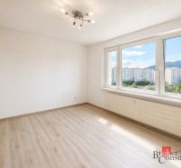 Ein Zimmer mit großen Fenstern und einem Boden in Holzoptik in einer 3-Zimmer-Wohnung.