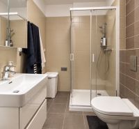 Badezimmer in einer 2-Zimmer-Wohnung mit moderner Duschkabine, eingebautem Waschbecken und hellen Fliesen.