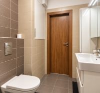 Badezimmer in einer 2-Zimmer-Wohnung mit Fliesen und hängender Toilette.