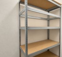 Ein Metallregal mit Regalböden in einer 2-Zimmer-Wohnung an einer weißen Wand und einem grauen Boden.