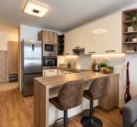 Küche in einer 2-Zimmer-Wohnung mit Geräten und Bodenbelag in Holzoptik.