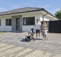 Ein Einfamilienhaus in Hôrka nad Váhom mit einer Familie auf der gepflasterten Zufahrt.