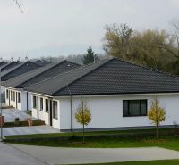 Einfamilienhäuser mit dunklem Dach in Hôrka nad Váhom, umgeben von Grün und einer Straße.