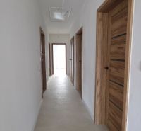 Der Flur in einem Einfamilienhaus mit Holztüren und beigem Boden.