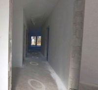 Ein Flur in einem Einfamilienhaus mit unfertigem Boden und nackten Wänden.