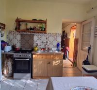 Küche in einem Einfamilienhaus mit Holzmöbeln, Kühlschrank und Elektroherd.