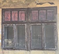 Abgebröckelter Putz und altes Holzfenster an einem Einfamilienhaus in Hejce.