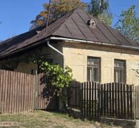 Ein älteres Einfamilienhaus in Hejce mit einem Schrägdach und einem Holzzaun.