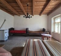 Ein Zimmer in einem Einfamilienhaus mit Holzbalkendecke und Kachelofen.