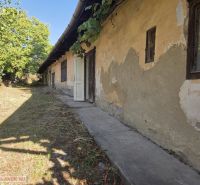 Ein Einfamilienhaus in Hejce, das renoviert werden muss, mit altem Putz und einem gepflegten Garten.