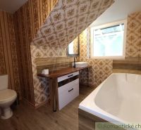 Badezimmer in einem Einfamilienhaus mit Tapeten und Bodenbelag in Holzoptik.