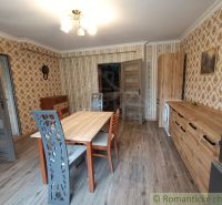 Esszimmer in einem Einfamilienhaus mit gemusterten Tapeten und einem Boden in Holzoptik.
