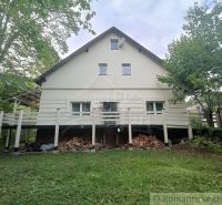 Ein Einfamilienhaus in Staškov, umgeben von Grün, mit Holz unter der Terrasse gelagert.