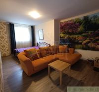 Wohnzimmer in einem Einfamilienhaus mit einem orangefarbenen Sofa und einer Naturtapete.