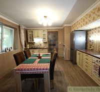 Eine Küche in einem Einfamilienhaus mit gemusterten Tapeten und einem Boden in Holzoptik.