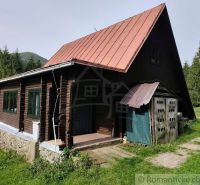 Eine Hütte in Rajecká Lesná mit einem Blechdach und Holzwänden, umgeben von Natur.