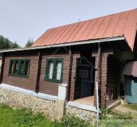 Eine Holzhütte mit Blechdach in der Natur von Rajecká Lesná, umgeben von Grün.