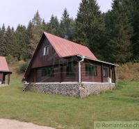 Eine Hütte in Rajecká Lesná mit rotem Dach, Wald und grasbewachsener Umgebung.