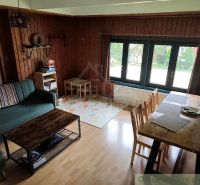Wohnzimmer der Hütte mit einem bequemen Sofa und einem Tisch, Boden mit Holzdekor.