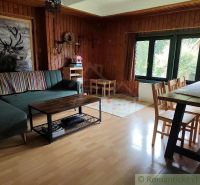 Wohnzimmer in einer Hütte mit gemütlicher Sitzecke und Boden in Holzoptik.