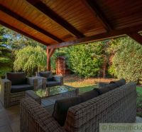 Überdachte Terrasse eines Einfamilienhauses in Bernolákovo mit Rattanmöbeln, umgeben von Grün.