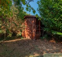 Ein Holzunterstand, umgeben von dichtem Grün, im Garten eines Einfamilienhauses in Bernolákovo.