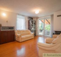 Wohnzimmer in einem Einfamilienhaus mit cremefarbenen Sofas und einem Boden in Holzoptik.