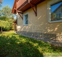 Ein Einfamilienhaus in Bernolákovo mit einem Steinsockel, umgeben von Grün und Bäumen.