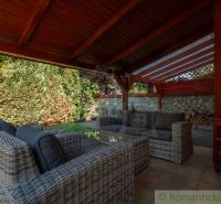 Die Terrasse des Einfamilienhauses in Bernolákovo mit Rattanmöbeln und einem Holzdach.