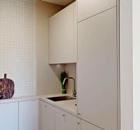 Küchenbereich in einer 2-Zimmer-Wohnung mit sauberer weißer Fliesenverkleidung und Spülbecken.