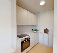 Küche in einer 2-Zimmer-Wohnung mit weißen Schränken und einem Boden in Holzoptik.