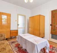 Ein Zimmer in einer 2-Zimmer-Wohnung mit älteren Möbeln und einem Boden in Holzoptik.