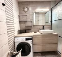Badezimmer in einer 3-Zimmer-Wohnung mit Waschmaschine, Waschbecken und dekorativen Fliesen.