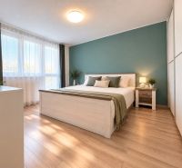 Helles Schlafzimmer mit Bett, Schrank und Holzboden in einer 3-Zimmer-Wohnung.