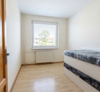 Helles Zimmer in einer 3-Zimmer-Wohnung mit Holzboden und Bett.