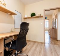 Arbeitsbereich mit Schreibtisch und schwarzem Bürostuhl, ergänzt durch einen Boden mit Holzdekor.