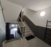 Treppenhaus eines Apartmenthauses in einer 3-Zimmer-Wohnung mit modernen Fliesen und Geländer.