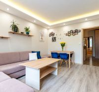 Wohnzimmer in einer 3-Zimmer-Wohnung mit Sofa, Tisch und Holzboden.