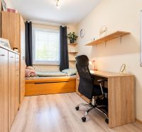Ein Arbeitszimmer mit Bett, Schreibtisch und Regal, Holzboden in einer 3-Zimmer-Wohnung.