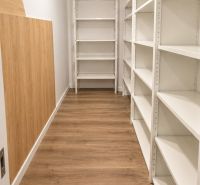 Stauraum mit weißen Regalen und einem Boden in Holzoptik in einer 2-Zimmer-Wohnung.